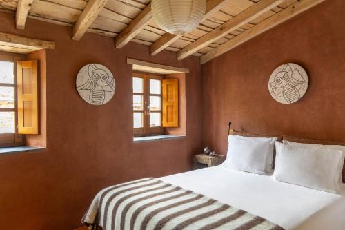 a bedroom with a white bed and windows at Cerdeira - Home for Creativity in Lousã