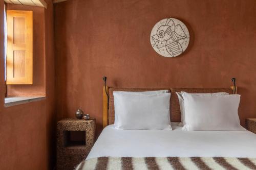1 cama con almohadas blancas y reloj en la pared en Cerdeira - Home for Creativity, en Lousã