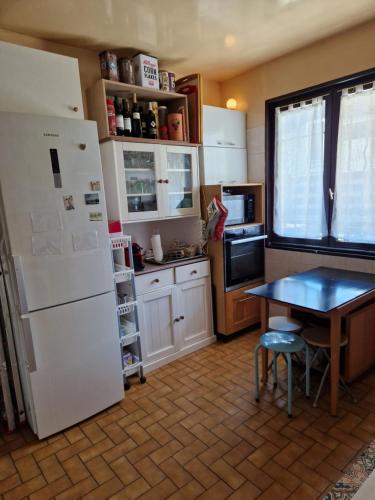 a kitchen with a white refrigerator and a table at Chez Gabrielle in Gaillard