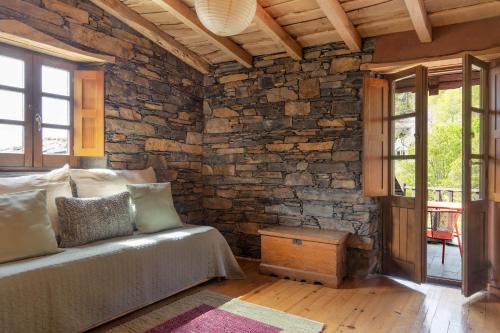 a bedroom with a bed and a stone wall at Cerdeira - Home for Creativity in Lousã