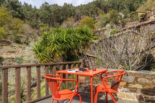 a red table and two chairs on a balcony at Cerdeira - Home for Creativity in Lousã