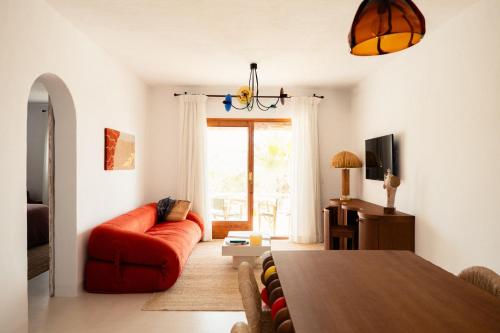 a living room with a red couch and a table at Petunia Ibiza, a Beaumier hotel in Cala Vadella