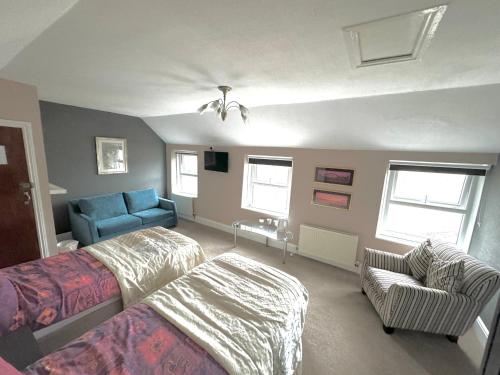 ein Schlafzimmer mit einem Bett, einem Sofa und einem Stuhl in der Unterkunft Ashfield Guesthouse in Douglas