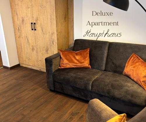 a brown couch with orange pillows in a living room at Hotel Schwaiger in Glonn