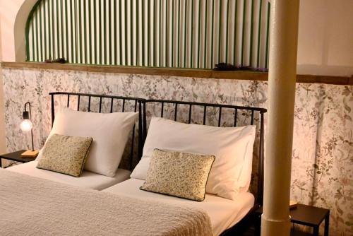 a bedroom with a bed with white sheets and pillows at Penzion Jízdárna Hejtmánkovice in Broumov