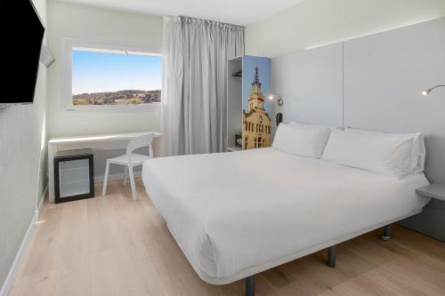 a bedroom with a large white bed and a desk at B&B HOTEL Barcelona Granollers in Les Franqueses del Vallès