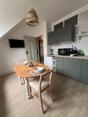 a kitchen with a wooden table with chairs and a dining room at Appartement charmant et confortable en centre-ville in Condé-sur-Noireau