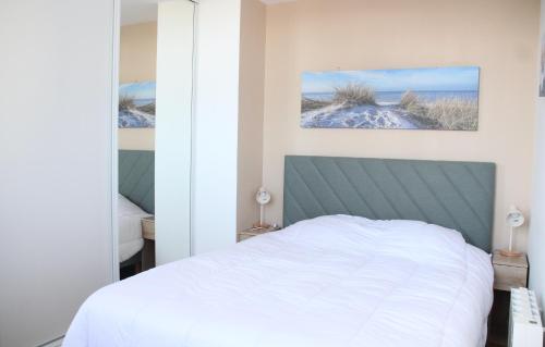 - une chambre avec un lit blanc et deux photos sur le mur dans l'établissement Le Freesia, à 20m de la plage, 5 min du centre-ville, à Roscoff