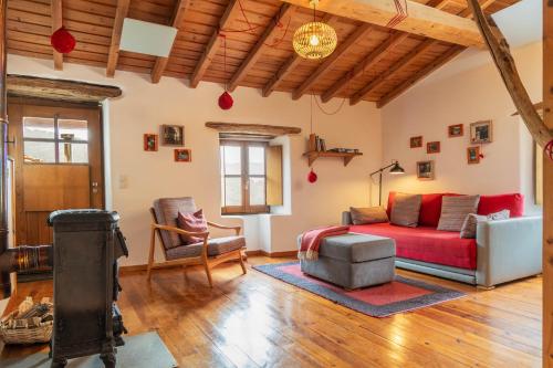 a living room with a red couch and a chair at Cerdeira - Home for Creativity in Lousã