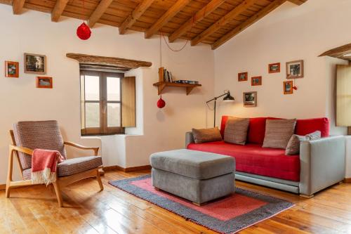 a living room with a red couch and a chair at Cerdeira - Home for Creativity in Lousã