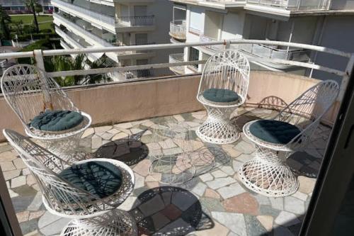 quatre chaises en osier assises sur une terrasse sur un balcon dans l'établissement Nice Flat With Terrace On The Croisette, à Cannes