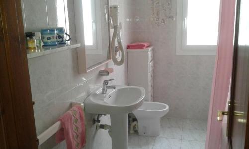 a white bathroom with a sink and a toilet at Apartamentos Gabriel Sans in Fornells