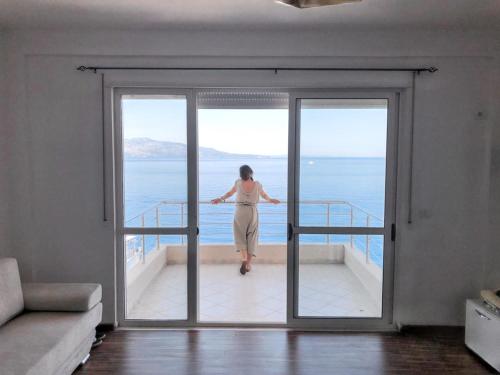 a woman standing on a balcony looking out at the ocean at Belle View Apartment in Sarandë