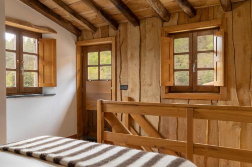 a room with wooden walls and windows and a bed at Cerdeira - Home for Creativity in Lousã