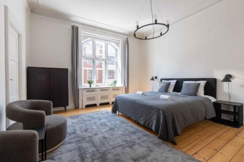a white bedroom with a bed and a chair at Lovely 3BR Manor Flat 5 min from Tivoli Gardens in Copenhagen