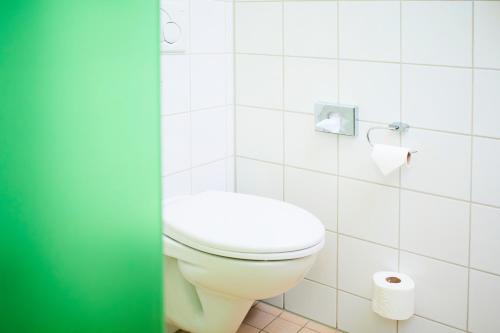 a white toilet in a bathroom with a roll of toilet paper at Gästehaus im LWH in Lingen