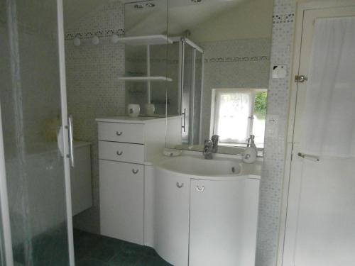 Un baño blanco con lavabo y espejo. en La Gentilliere, en Brunelles