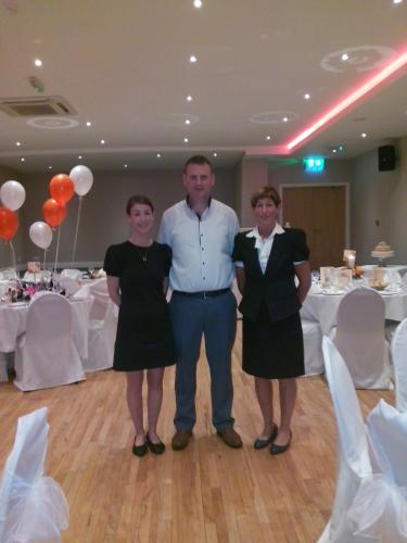 a group of three people standing in front of a table at Percy French Hotel in Strokestown