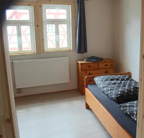 a bedroom with a bed and a dresser and two windows at Castillo in Ensheim