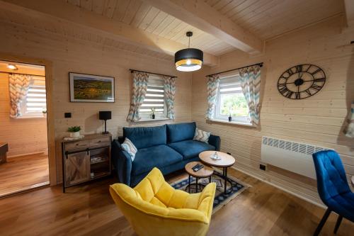 ein Wohnzimmer mit einem blauen Sofa und einem Tisch in der Unterkunft Domki u Sosny in Brenna
