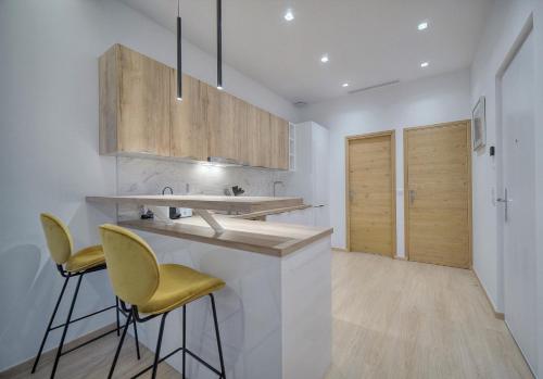 une cuisine avec des comptoirs blancs et des chaises jaunes dans l'établissement Idéal 2 pièces rénové proche Palais 2P1, à Cannes