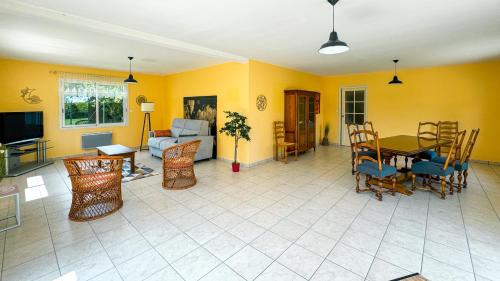 - un salon avec des murs jaunes, une table et des chaises dans l'établissement Grande et belle maison à 5 minutes de la mer, à Penvénan