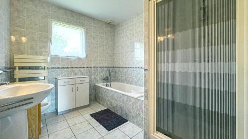 une salle de bain avec une baignoire, un lavabo et une douche dans l'établissement Grande et belle maison à 5 minutes de la mer, à Penvénan