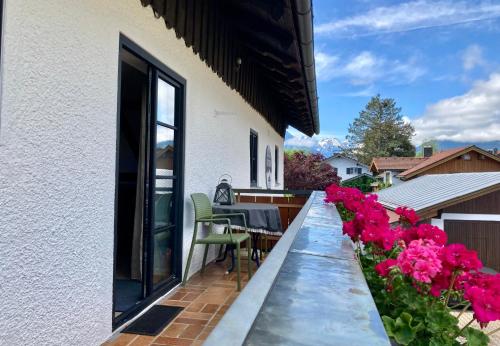 a balcony with pink flowers and a table and chairs at Schittlerhof in Fischen
