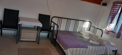 a bed in a room with a table and chairs at Garičkina kuća 2 in Pirot