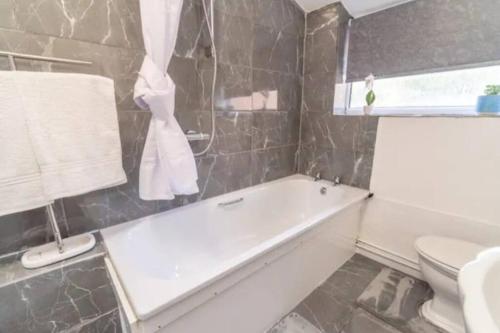 a bathroom with a bath tub and a toilet at Beautiful Home near City Centre in Nottingham
