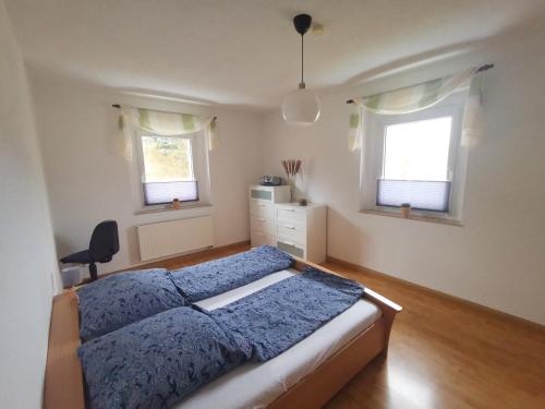 a bedroom with a blue bed and two windows at Ferienwohnung Bimmelbahn Blick in Kurort Oberwiesenthal
