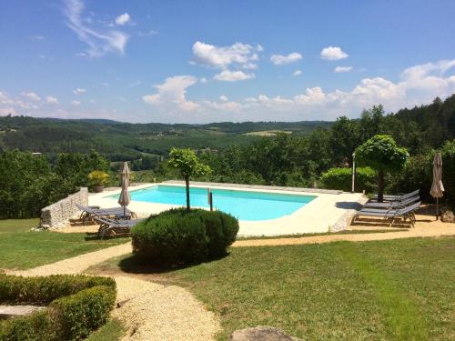 - une piscine avec 2 chaises longues et des parasols dans l'établissement Les Trois Collines, à Saint-Cybranet
