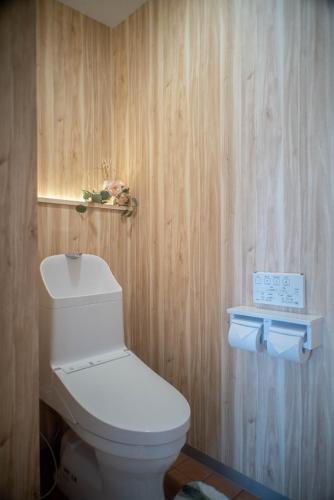 a bathroom with a white toilet and a wooden wall at Rakuyado Shinimamiya in Osaka