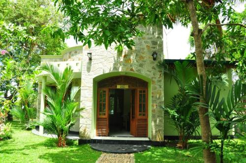 a stone house with a wooden door in a yard at Hotel Sobana Lake front in Udawalawe