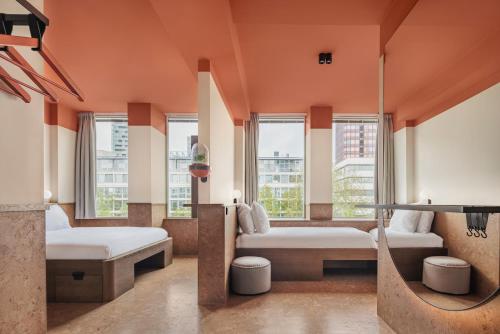 a bedroom with two beds and windows and a tv at The Usual Rotterdam in Rotterdam