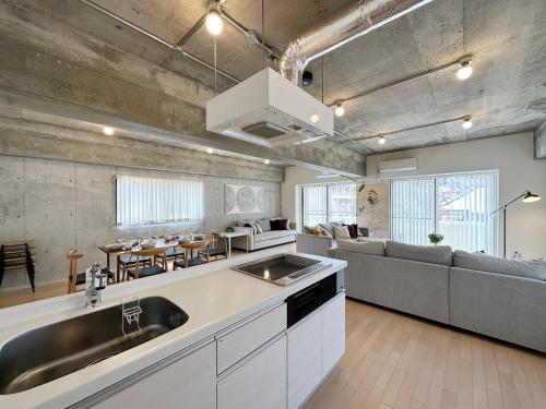 a kitchen and living room with a sink and a couch at b hotel M's lea - Modern Spacious Apartment Beside Peace Park 10 ppl in Hiroshima
