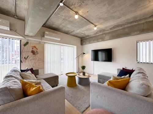 a living room with two couches and a flat screen tv at b hotel M's lea - Modern Spacious Apartment Beside Peace Park 10 ppl in Hiroshima