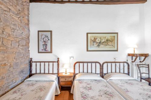 2 camas en una habitación con una pared de piedra en Cal Masover, en Sant Boi de Lluçanès