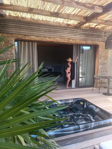 a woman in a hat standing on a patio at Hôtel Les Suites Du Maquis in Bonifacio