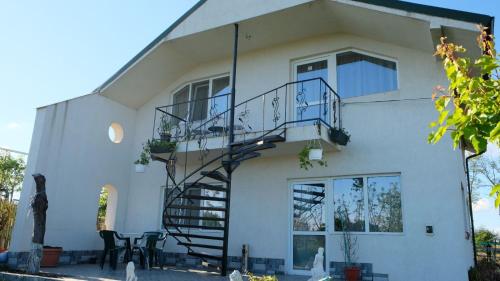 Una casa blanca con una escalera de caracol. en Casuta Morena, en Tuzla