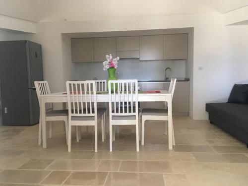 una mesa de comedor blanca con sillas y un jarrón de flores en il Trullo di Alice e Chiara, en Selva di Fasano