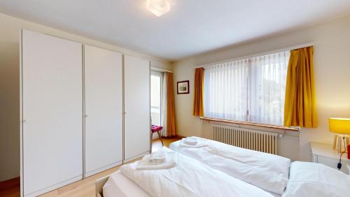 Un dormitorio con una cama y una ventana grande. en Daniela B, en St. Moritz