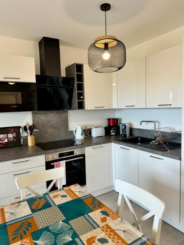 une cuisine avec des armoires blanches et une table et des chaises dans l'établissement T2 neuf vue mer proximite plage, à Propriano