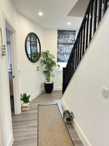 a hallway with stairs with potted plants and a mirror at JayGees luxury homes in Lower Gornal