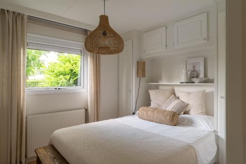 a white bedroom with a bed and a window at Chalet Boisée in Voorthuizen