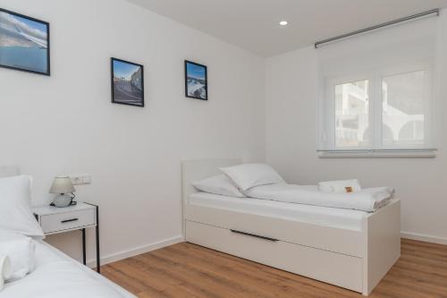 a white bedroom with a bed and a window at Villa Laganini Apartment 2&4 in Podaca