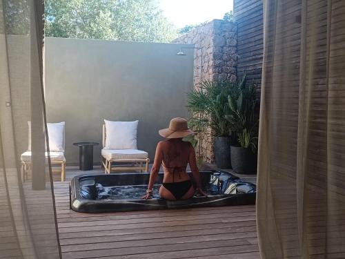 a woman in a hat sitting in a hot tub at Hôtel Les Suites Du Maquis in Bonifacio