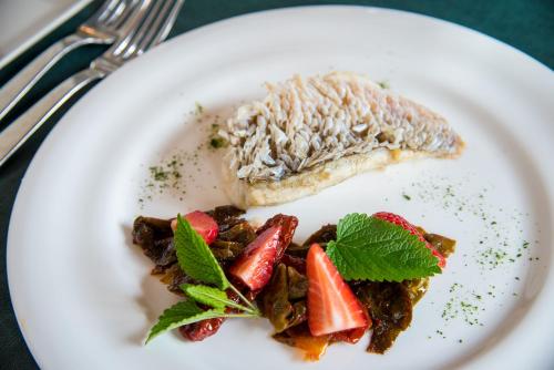 a plate of food with a piece of fish and strawberries at Hotel Ristorante Magia del Brenta in Fiesso dʼArtico