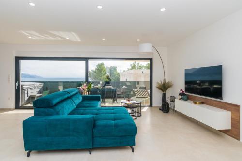 a living room with a blue couch and a large window at Villa Laganini Apartment 2&4 in Podaca