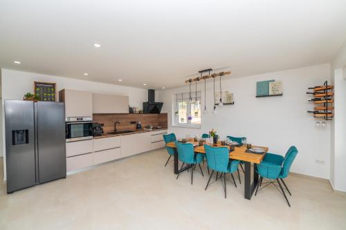 a kitchen with a dining room table and blue chairs at Villa Laganini Apartment 2&4 in Podaca